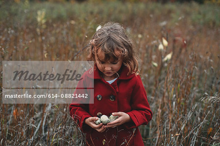 Girl holding wildflower pods in field of long grass