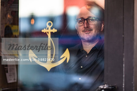 Portrait of barman looking through public house window, Brooklyn, New York, USA