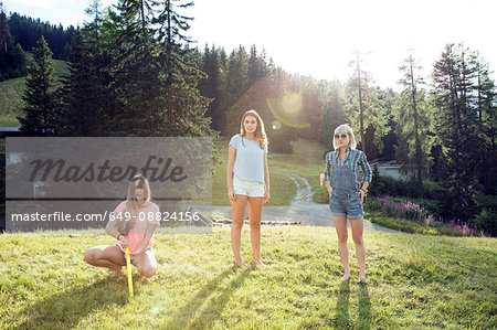 Portrait of three adult female friends standing and crouching in field, Sattelbergalm, Tirol, Austria