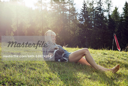 Mid adult woman reclining in sunlit field, Sattelbergalm, Tirol, Austria