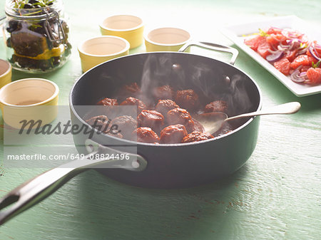Saucepan of steaming greek meatballs on table
