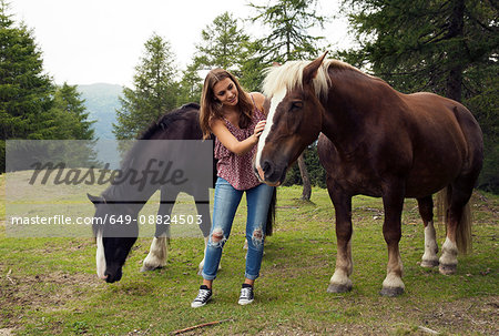 Young woman stroking palomino horse on hill, Sattelbergalm, Tyrol, Austria