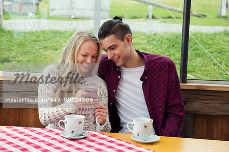 Young couple looking at smartphone update in cafée