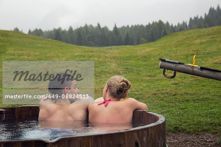 Rear view of young couple relaxing in rural hot tub, Sattelbergalm, Tyrol, Austria