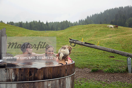 Four adult friends relaxing in rural hot tub, Sattelbergalm, Tyrol, Austria