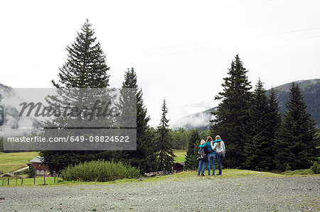 Rear view of three female friends looking out at landscape, Sattelbergalm, Tyrol, Austria