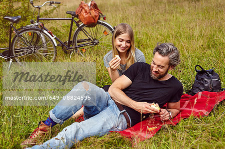 Couple eating apples at picnic in rural field