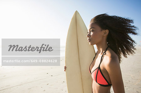Beautiful young female surfer gazing out from beach, Cape Town, Western Cape, South Africa