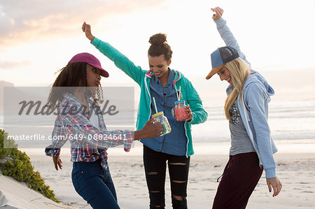 Three young female friends dancing together on beach, Cape Town, Western Cape, South Africa