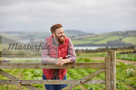 Man on farm leaning against gate looking away