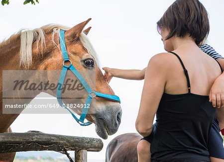 Mother and son stroking horse