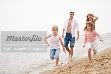 Family running along sandy beach