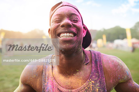 Portrait of young man at festival, covered in colourful powder paint