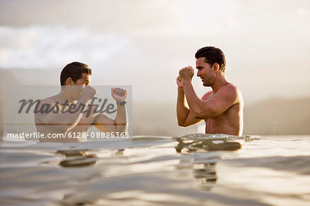 Two men challenge each other in a boxing pose as they stand in the sea.