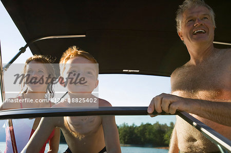 Young boy and his mature grandparents on a boat.