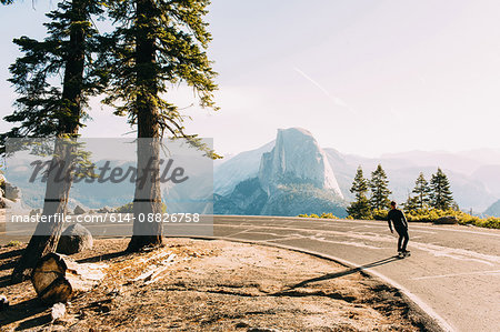 Skateboarder travelling on mountain road, Yosemite, California, USA