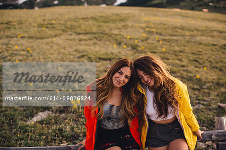 Friends sitting side by side looking at camera smiling, Rocky Mountain National Park, Colorado, USA