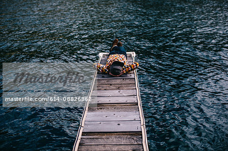 Young man lying down on pier at Shaver Lake, California, USA