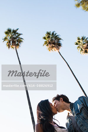 Young couple walking outdoors, kissing, low angle view