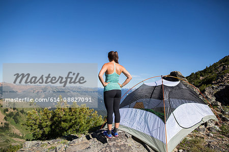 Hiker enjoying view beside tent on hilltop, Enchantments, Alpine Lakes Wilderness, Washington, USA
