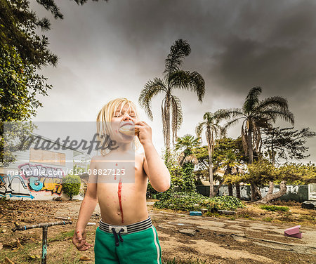 Boy eating treat with jam dripping down chest