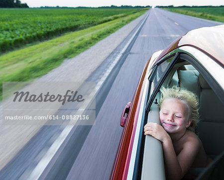 Windswept boy in car eyes closed smiling