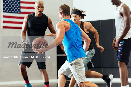 Male basketball player running with ball in basketball game