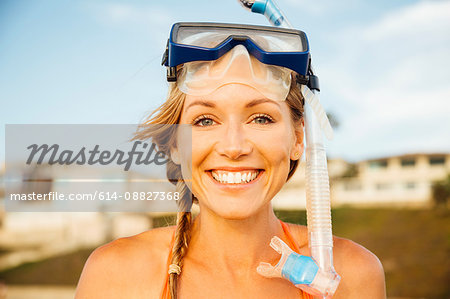 Portrait of woman wearing snorkel looking at camera smiling