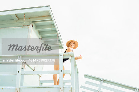 Woman wearing swimsuit on lifeguard tower looking away