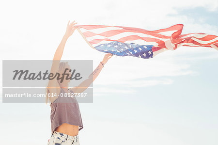 Woman with arms raised holding american flag