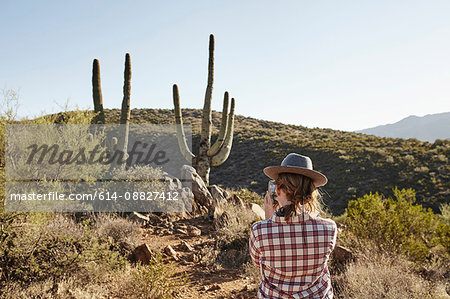 Woman photographing cacti, rear view, Sedona, Arizona, USA