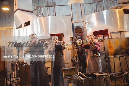 Team of glassblower shaping a glass on the blowpipe