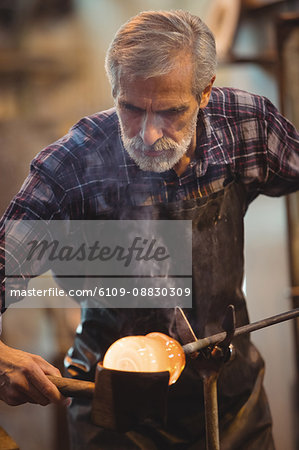 Glassblower forming and shaping a molten glass