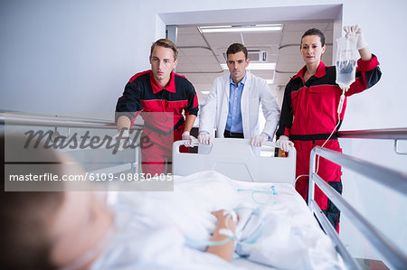 Doctors pushing emergency stretcher bed in corridor