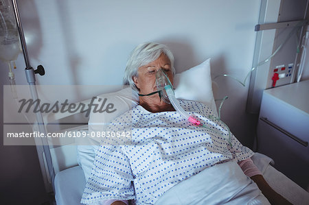 Senior patient lying on bed with oxygen mask on face
