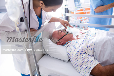 Female doctor putting oxygen mask on patient face