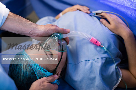 Hands of doctor placing oxygen mask on a pregnant woman face