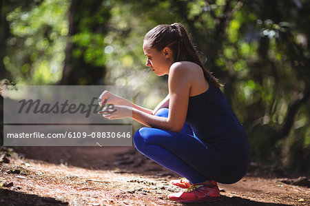 Woman in squatting position in forest walkway