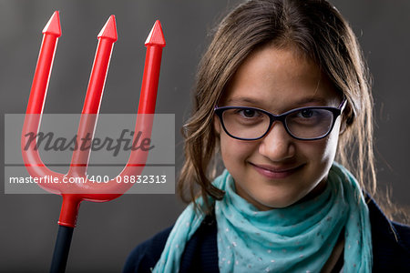 portrait of a little rascal girl with a red pitchfork meaning she is a little devil ready to make some pranks and jokes to have some fun
