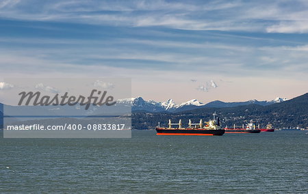 Vancouver harbor, ocean tankers waiting for loading in port on the background scenery of snow-capped mountains