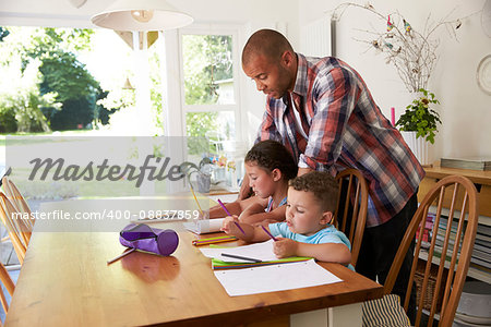 Father Helping Children With Homework At Table