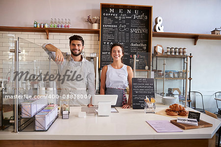 Couple ready to serve behind the counter of a coffee shop