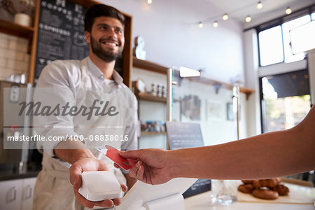 Barista takes credit card payment at a coffee shop, close up