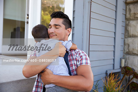 Father Hugging Son Sitting On Steps Outside Home