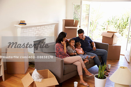 Family On Sofa Taking A Break From Unpacking Watching TV