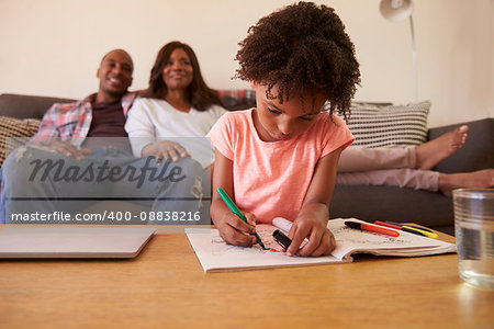 Parents Watch TV As Daughter Colors In Picture Book