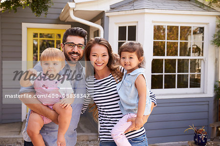 Portrait Of Excited Family Standing Outside New Home