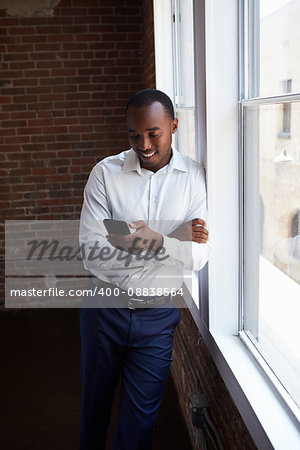 Businessman Checking Phone Standing By Office Window