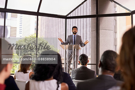 Hispanic man gesturing to audience at business seminar