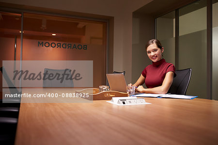 Young businesswoman working late in office smiles to camera